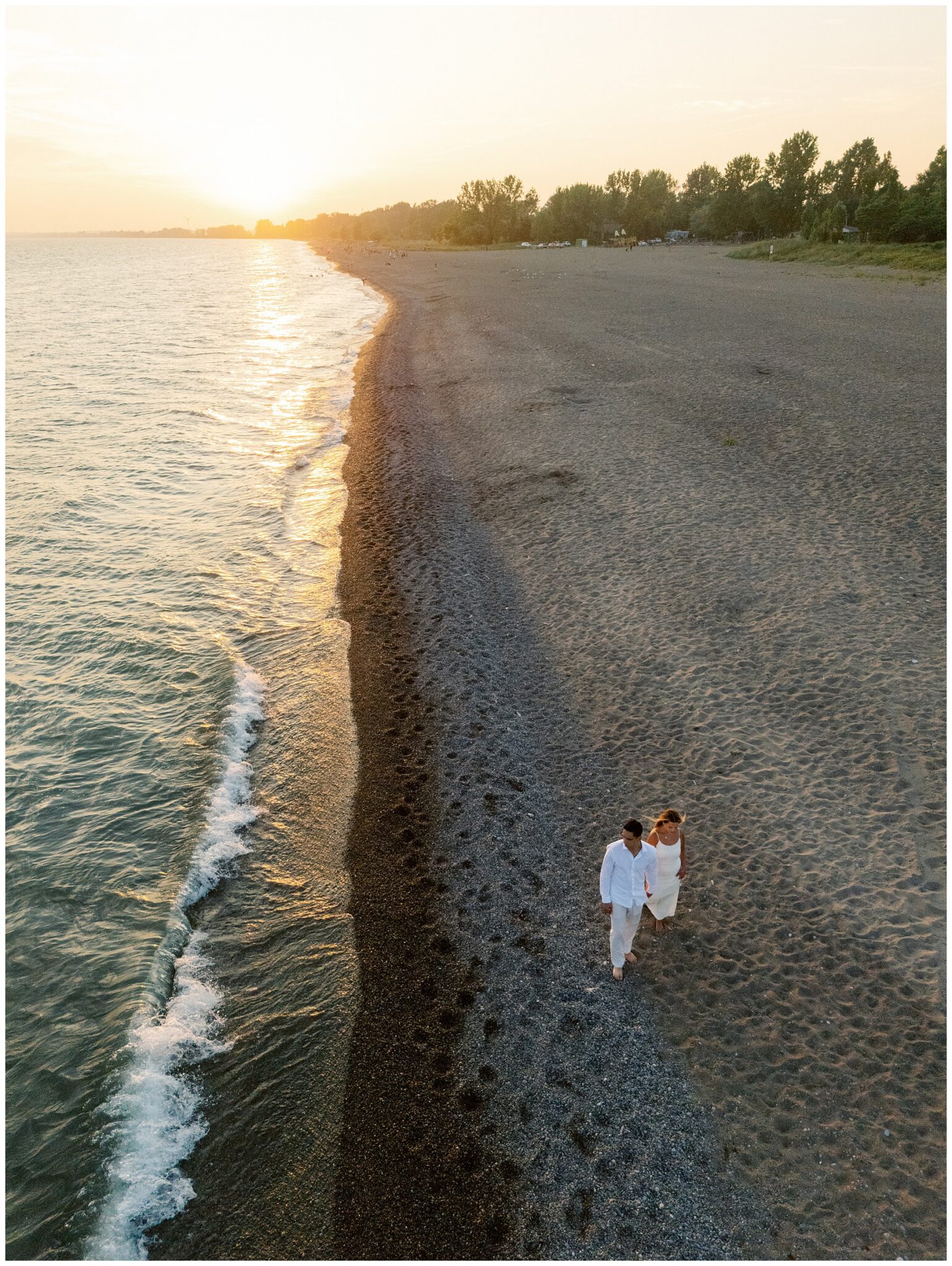 Aerial drone shot couple walking Erieau beach Lake Erie sunset Chatham-Kent